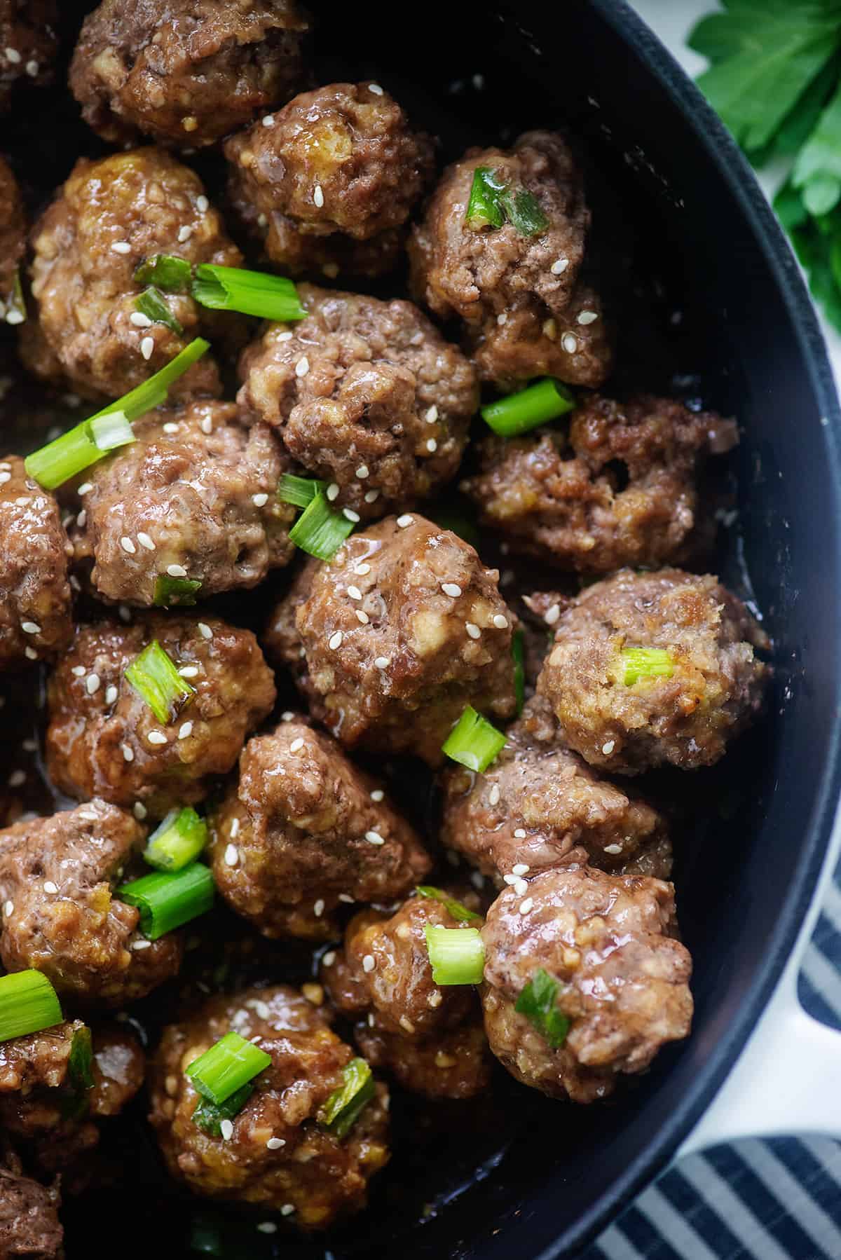 overhead view of meatballs in teriyaki sauce in black dish.