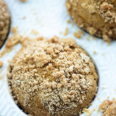A pumpkin muffin topped with streusel in a muffin tin.