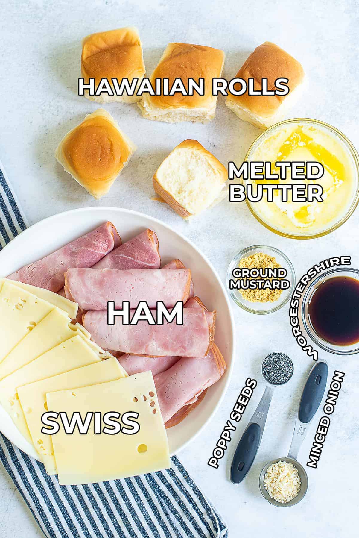 A top down view of all the ingredients used in the recipe including Hawaiian rolls, melted butter, ham, swiss, Worcestershire sauce, and seasoning.
