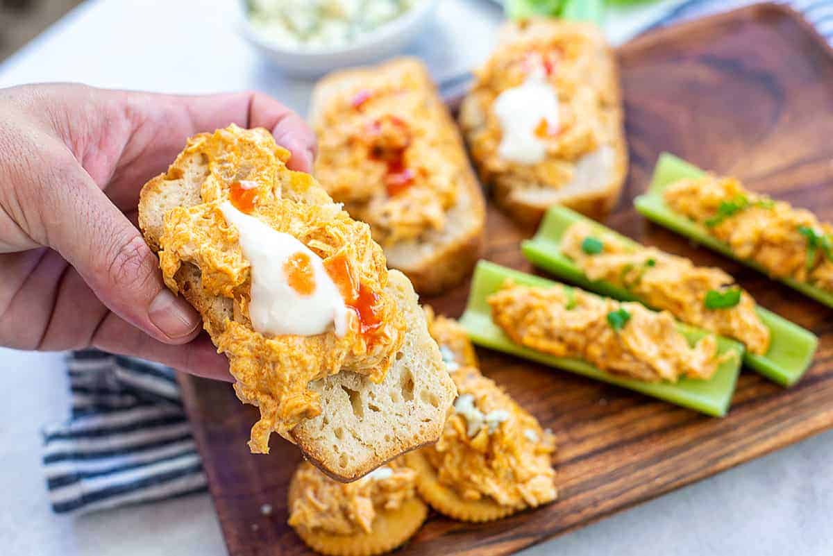 hand holding a piece of beer bread with buffalo chicken dip on top.