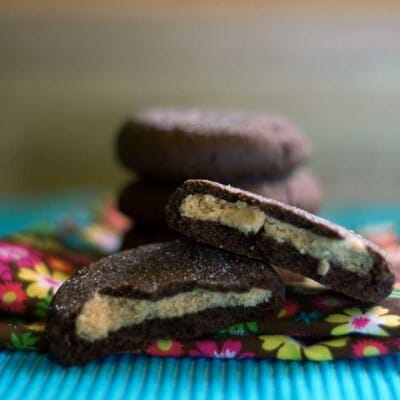 Two peanut butter filled chocolate cookies on a flower cloth napkin