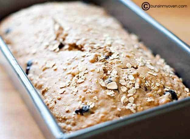 A close up of a loaf of oatmeal bread in a bread pan.