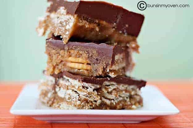 Small square white plate with three stacked up chocolate peanut butter candy bars on it.