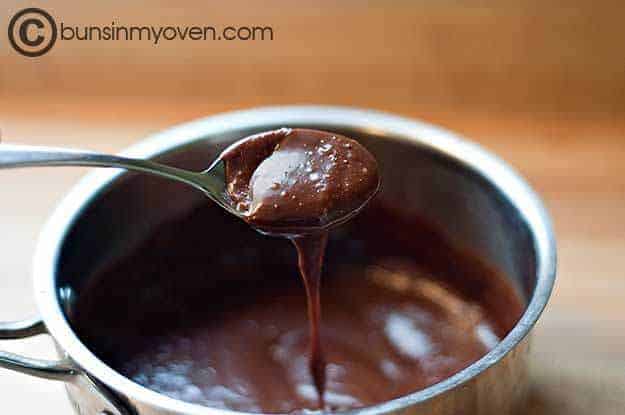 chocolate frosting drizzling from a spoon into a pot.