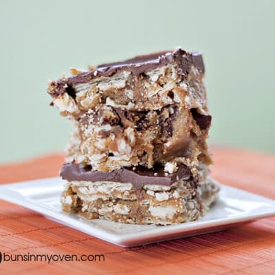 Stacked up chocolate peanut butter candy bars on a square white plate.