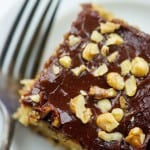 chocoalte frosted cake with walnuts on white plate with vintage fork