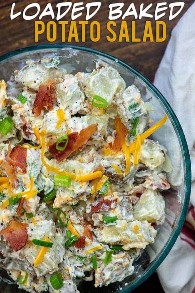 A clear glass bowl with salad and potatoes in it. 