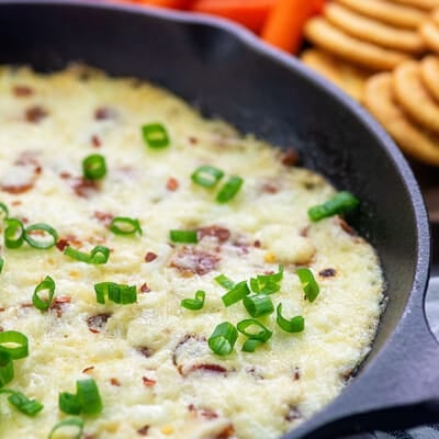 Cast iron skillet with melted cheese and green onions in it.