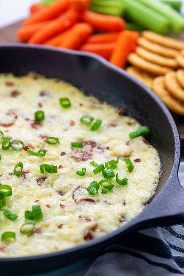 Cast iron skillet with melted cheese and green onions in it.