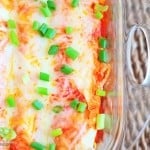 An overhead view of cheesy enchiladas in a clear glass baking pan