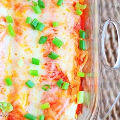 An overhead view of cheesy enchiladas in a clear glass baking pan