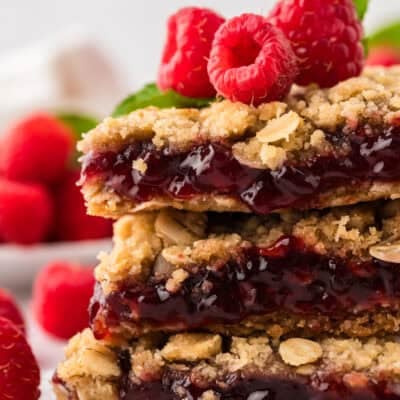 Raspberry oatmeal bars stacked together and topped with fresh berries.