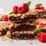 Raspberry oatmeal bars stacked together on counter.
