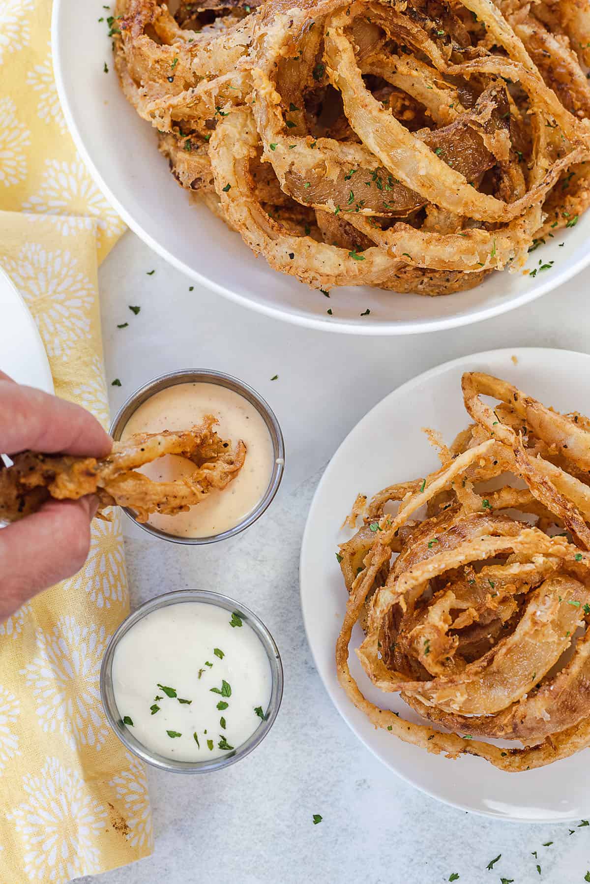 homemade onion strings being dipped in sauce.