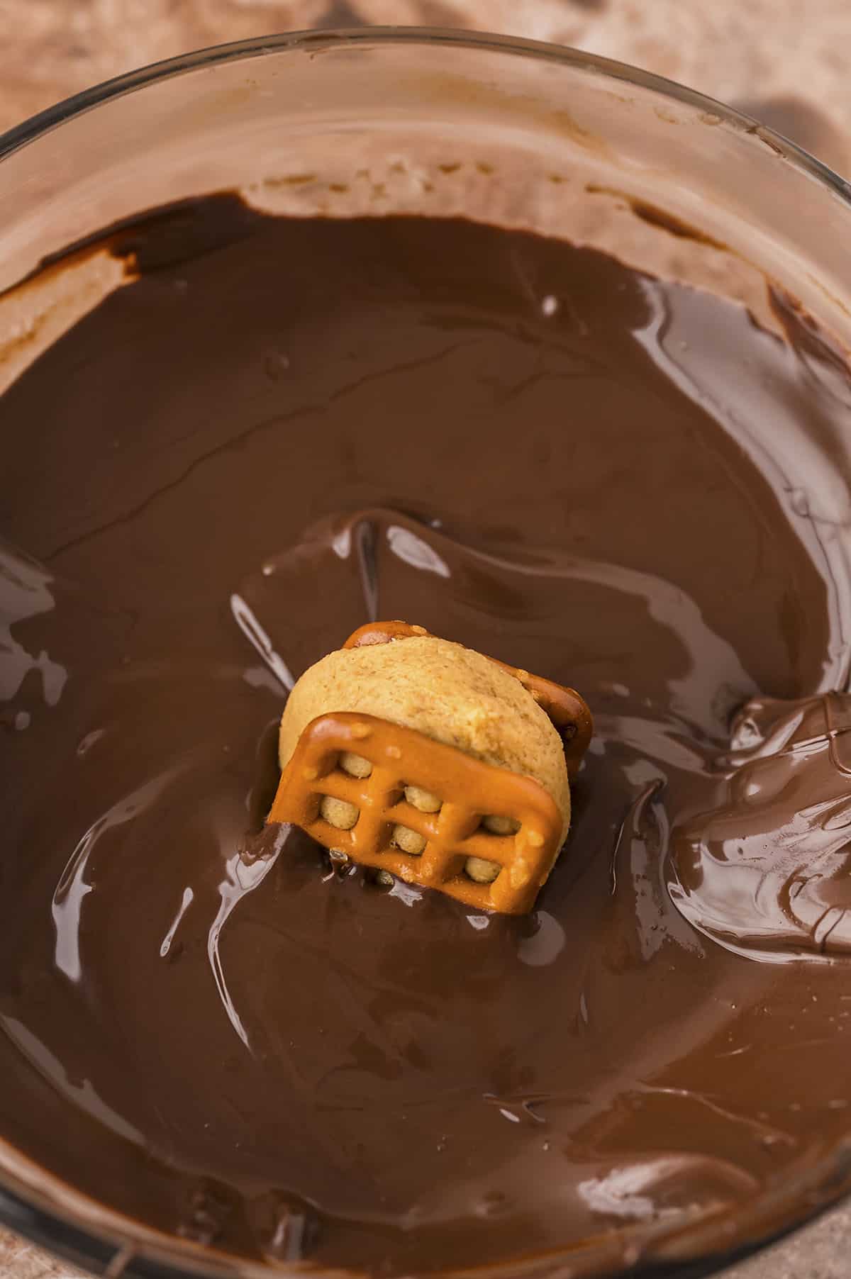 Pretzel bite being dunked in chocolate.