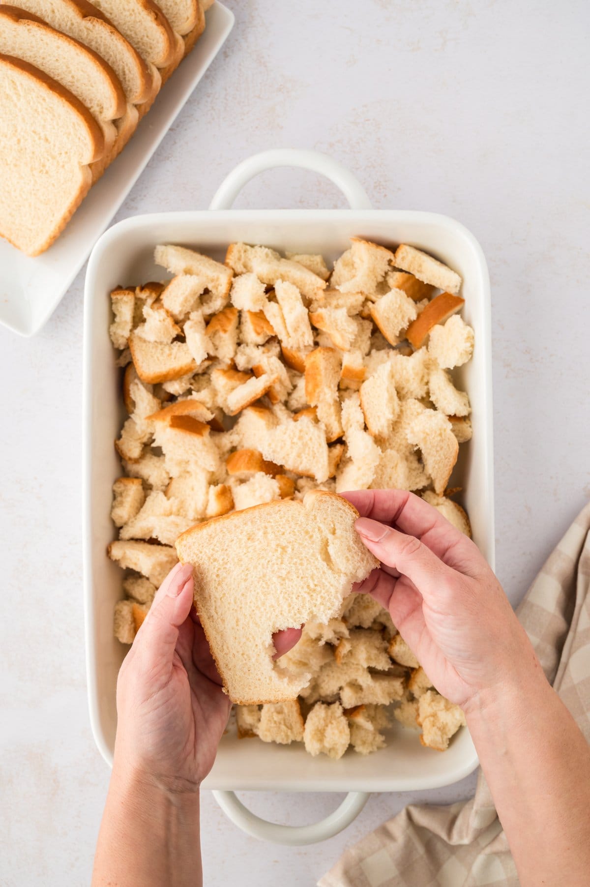 Hand tearing bread into bite-sized pieces.
