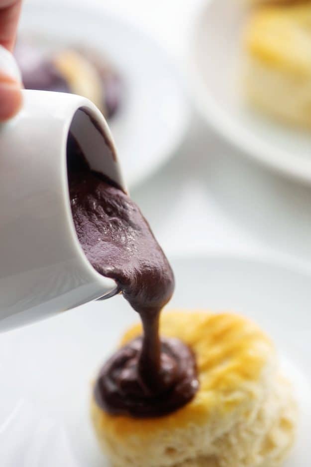 chocolate gravy being poured over biscuit.