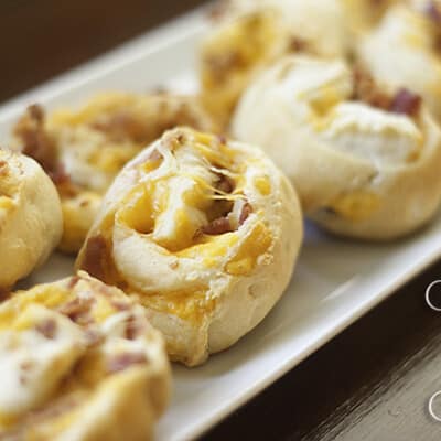 In the bacon and cheese pinwheels on a a long white plate