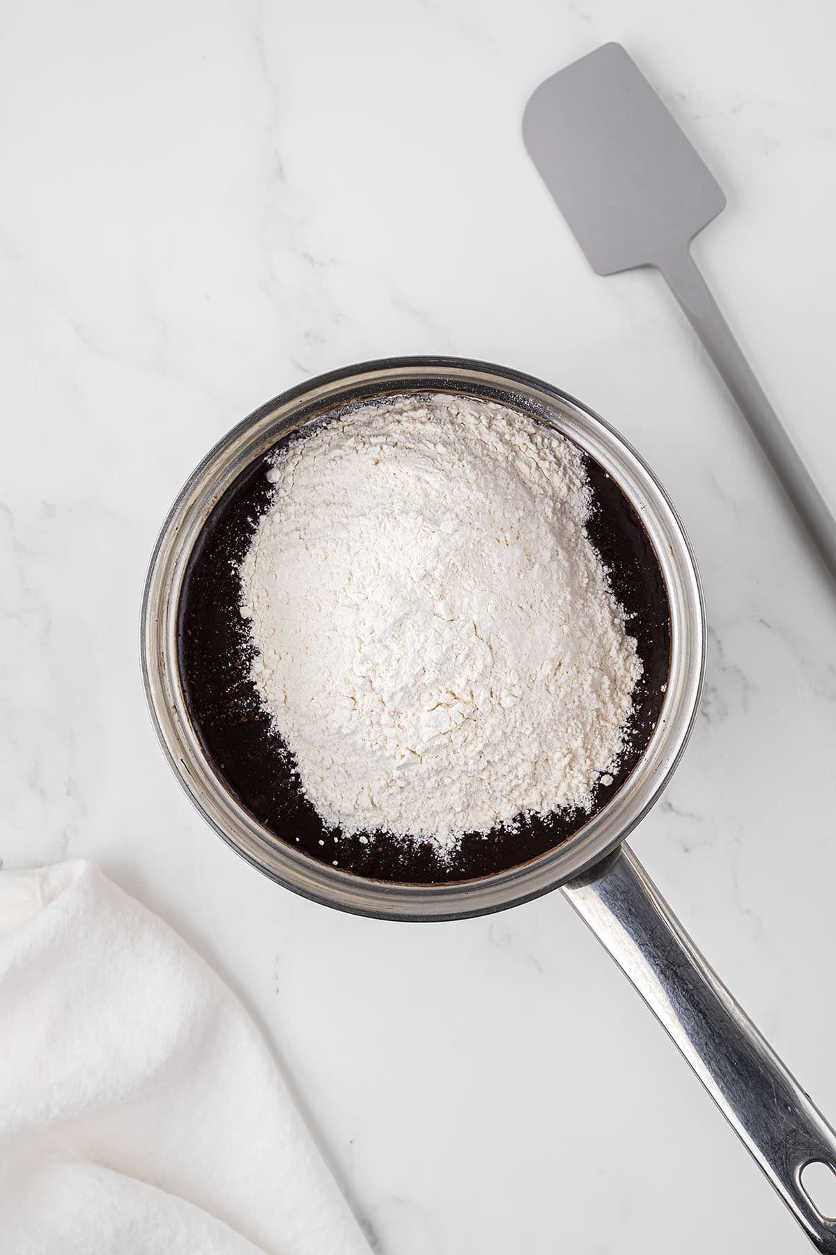 Dry ingredients added to melted chocolate to make brownies.