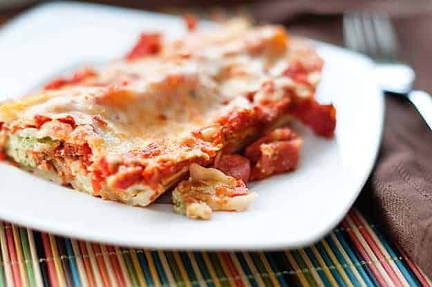 Close up of manicotti on a square white plate.