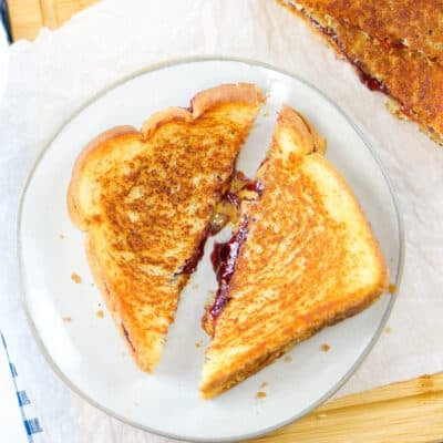 Grilled peanut butter and jelly sandwich on white plate.