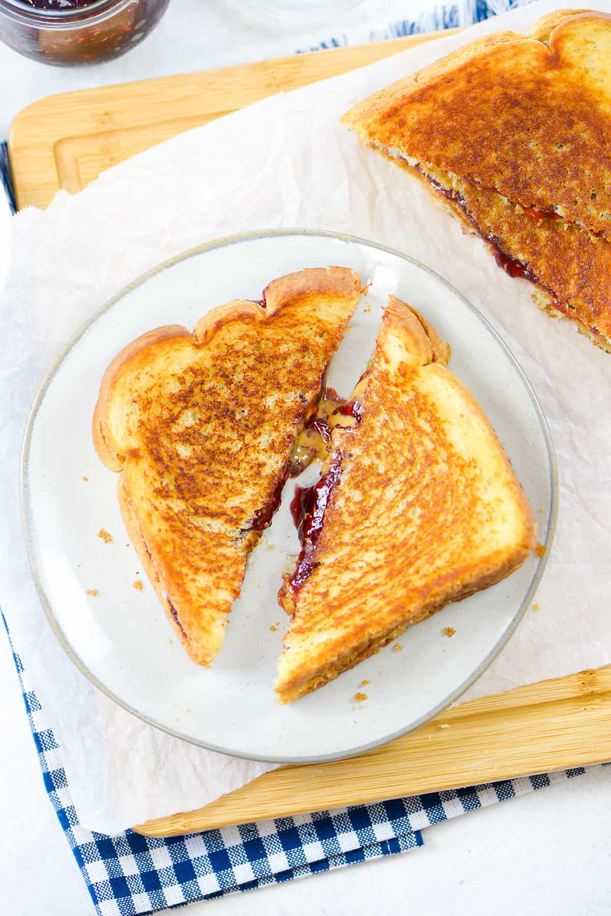 Grilled peanut butter and jelly sandwich on white plate.