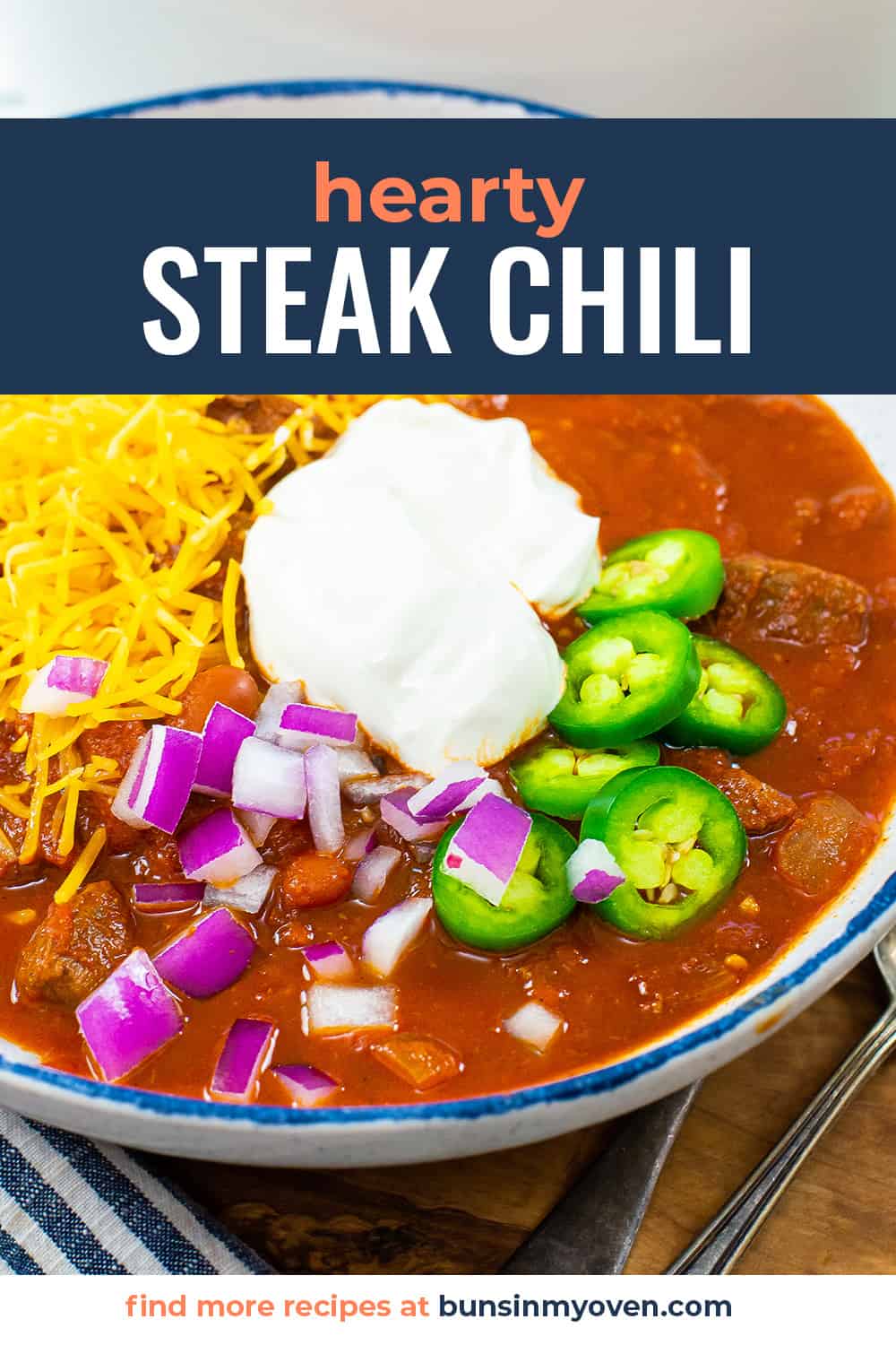 Steak chili in bowl with cheddar and sour cream on top.