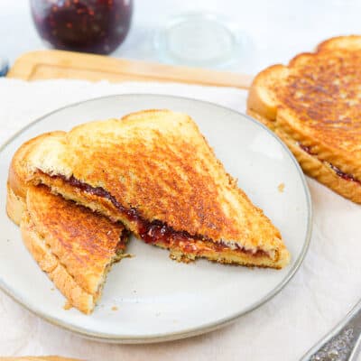 Peanut butter and jelly sandwich on white plate.