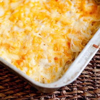 Melted cheese and shredded potatoes in a white baking dish.