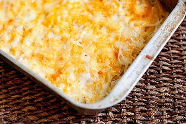 Melted cheese and shredded potatoes in a white baking dish.