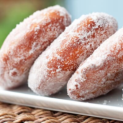 A row of sugared doughnuts on a white plate