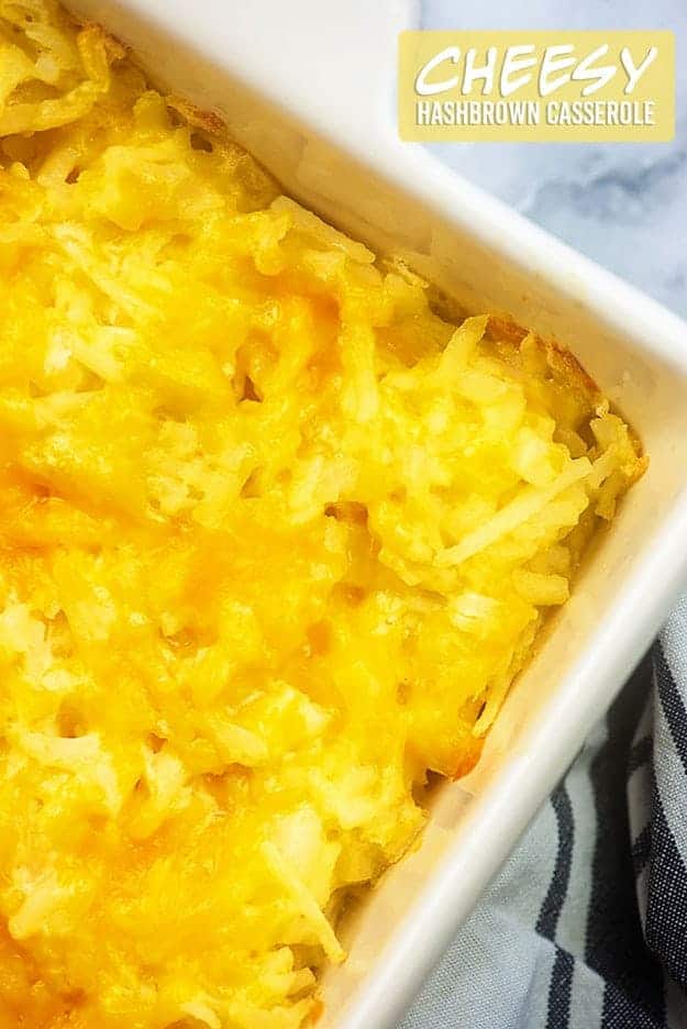 Shredded potatoes and melted cheese in a white nine by thirteen baking dish.