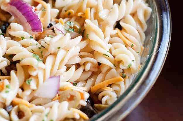 An overhead view of pasta salad in a clear glass bowl.