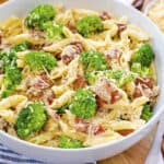 Penne Alfredo in bowl with bacon and broccoli.