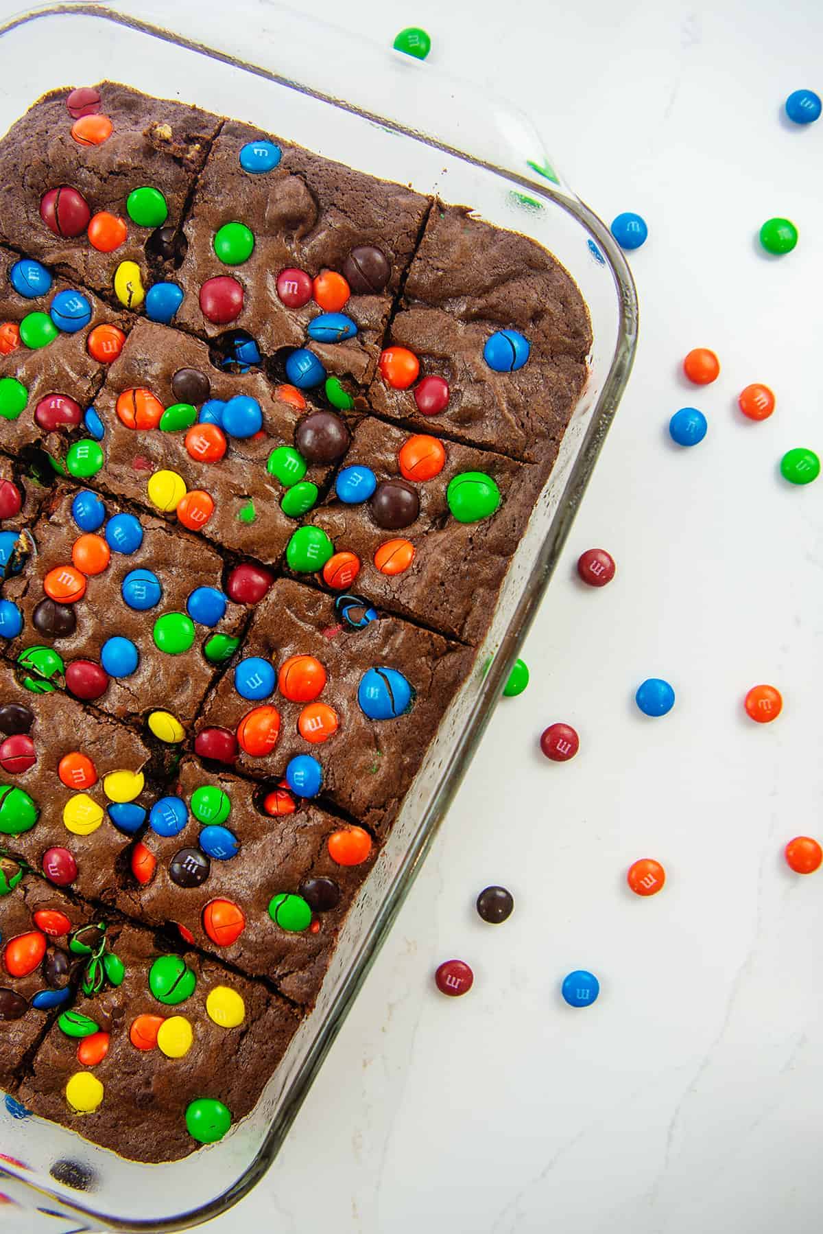 brownies topped with m&m's in glass baking dish.