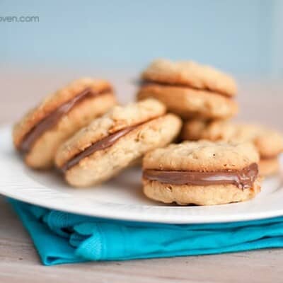 A plate of sandwich cookies on a folded blue napkin.