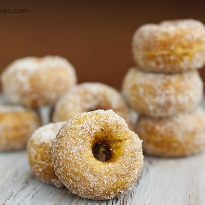A close up of stacked sugarcoated pumpkin doughnuts on a table