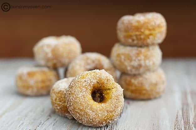 A close up of stacked sugarcoated pumpkin doughnuts on a table