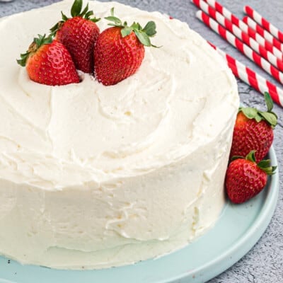 white frosting with berries on layer cake.