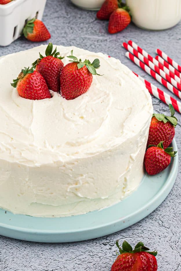 white frosting with berries on layer cake.