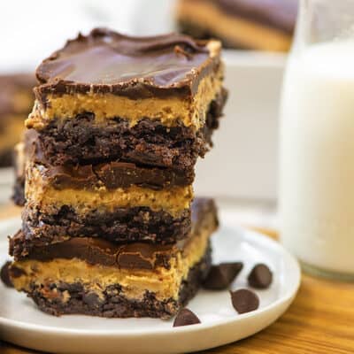 Buckeye brownies stacked together on white plate next to a glass of milk.