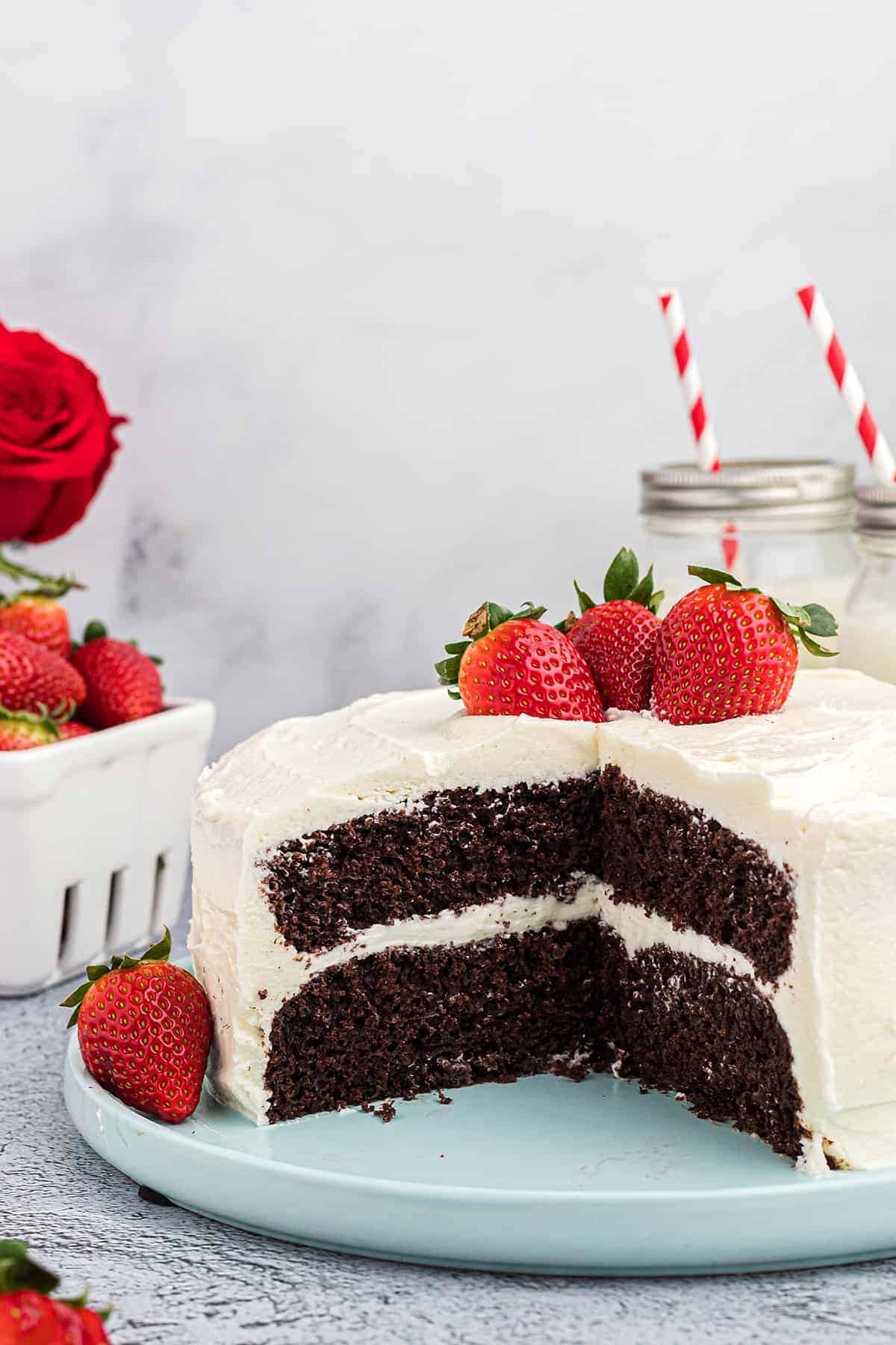 chocolate cake on cake plate with whipped frosting and berries.