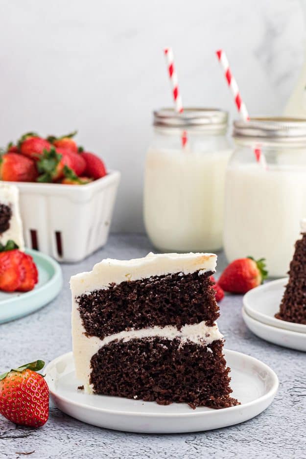 slice of chocolate cake with white frosting on plate.