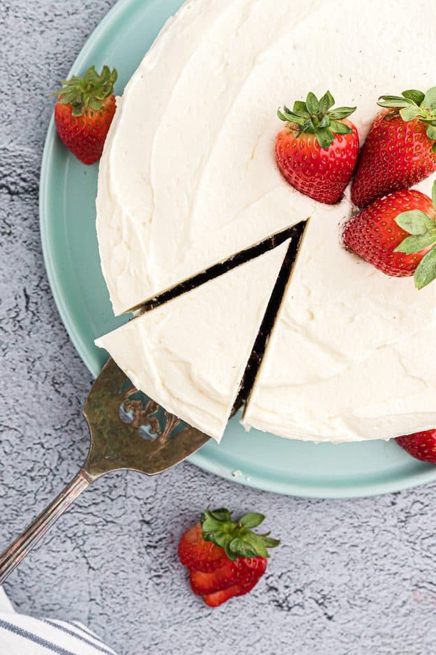 cut cake topped with whipped frosting and strawberries.