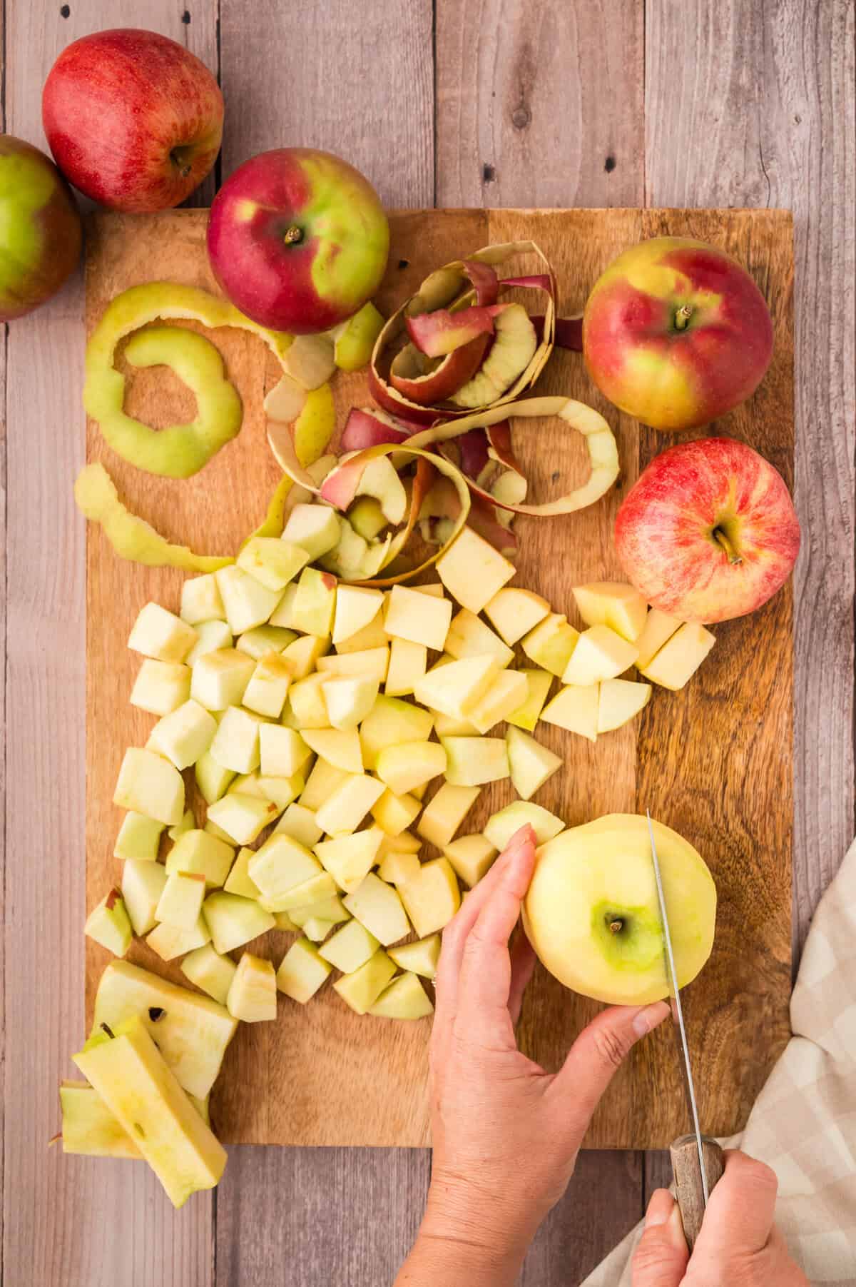 Peeled and chopped apples on wooden cutitng board.