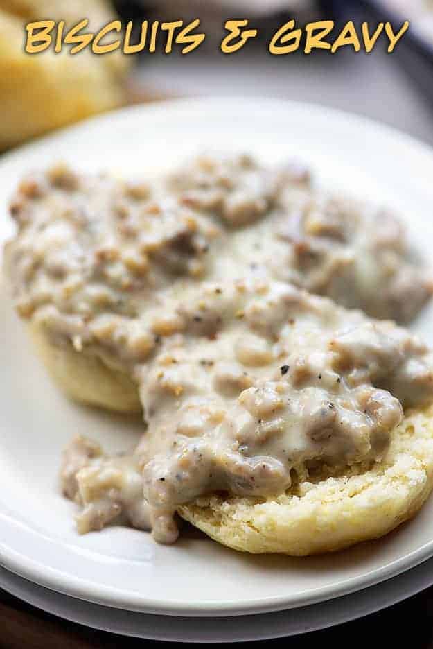 A close up of bisuits on a plate smothered in gravy.