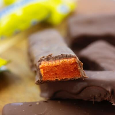 homemade Butterfinger candy bars piled up on wooden cutting board.