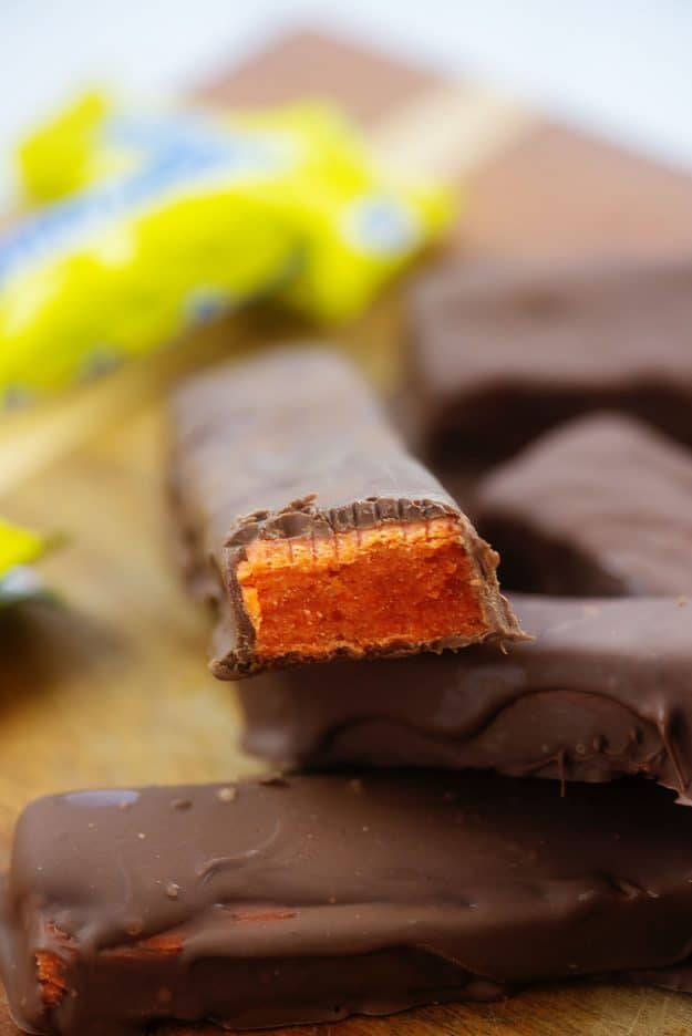 homemade Butterfinger candy bars piled up on wooden cutting board.