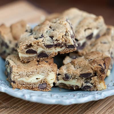 A plate with several chocolate chip cookie cheesecake bars on it.