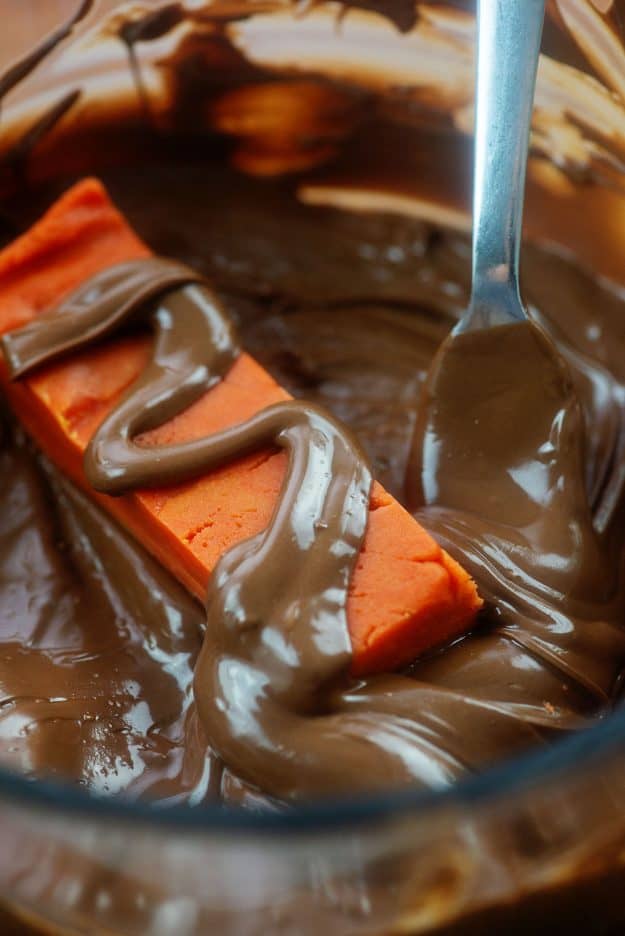 butterfinger candy bars being dunked in chocolate. 